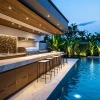 Cocina al aire libre con piscina y vegetación tropical.