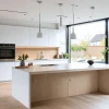 Cocina moderna y luminosa con muebles blancos y detalles de madera.
