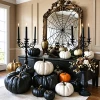 Decoración otoñal elegante con calabazas y velas negras.
